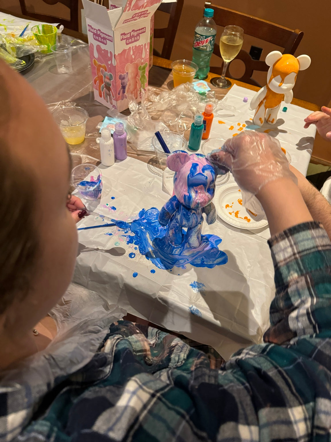 Guest pouring blue paint over a Drip Bear during a Boom Bear creative party experience