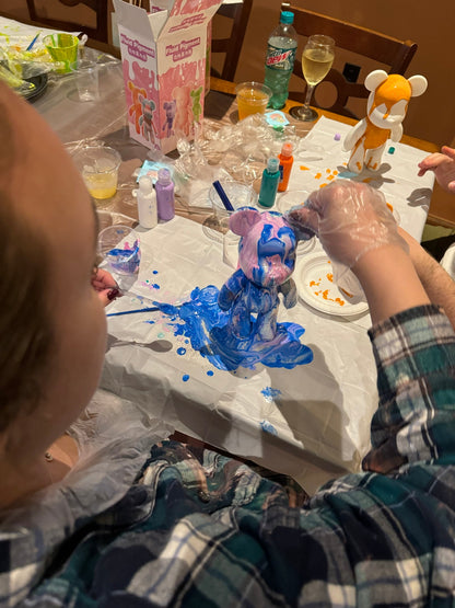 Guest pouring blue paint over a Drip Bear during a Boom Bear creative party experience