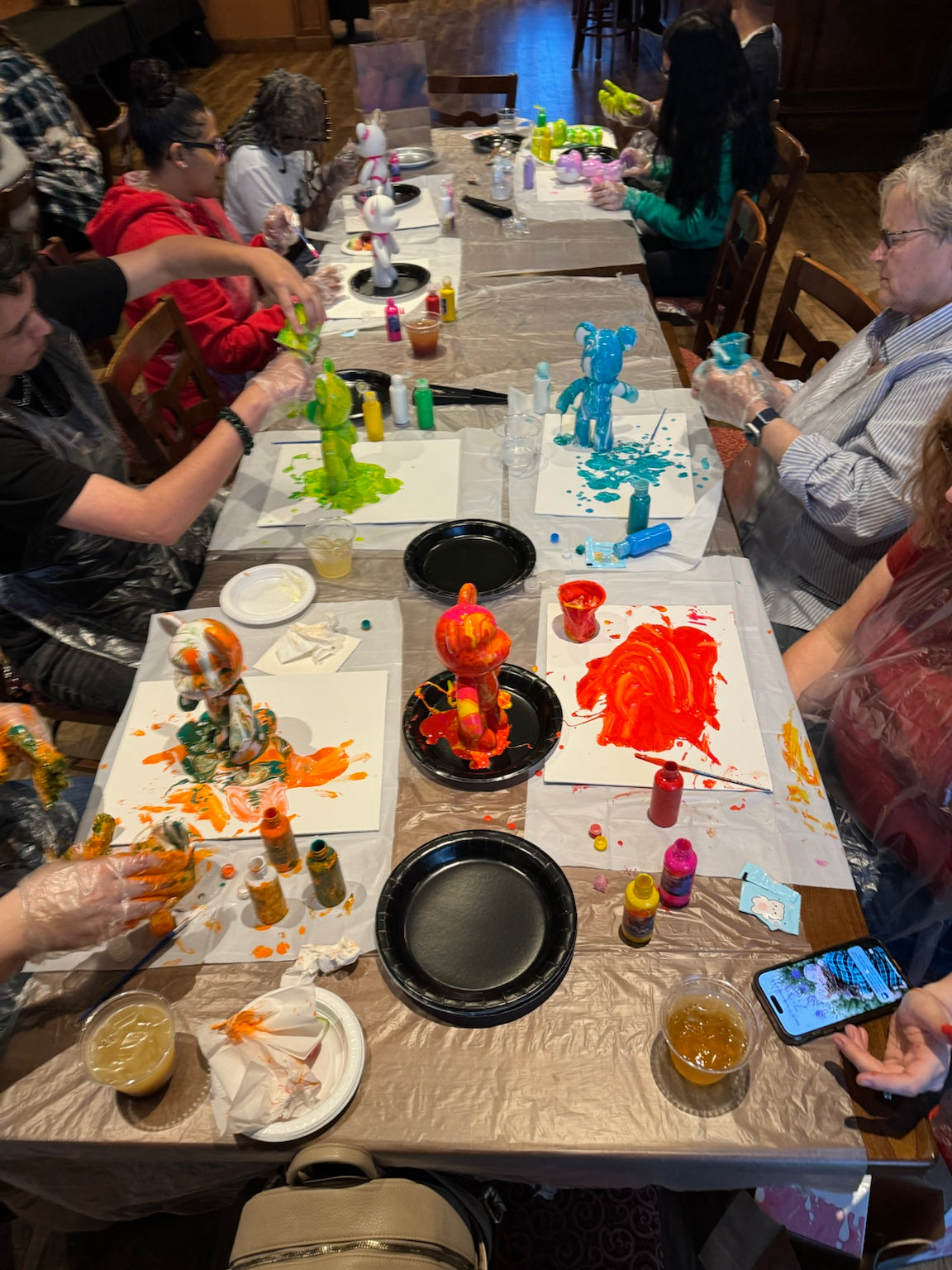 Full table of guests creating colorful bears during a Boom Bear mobile paint party