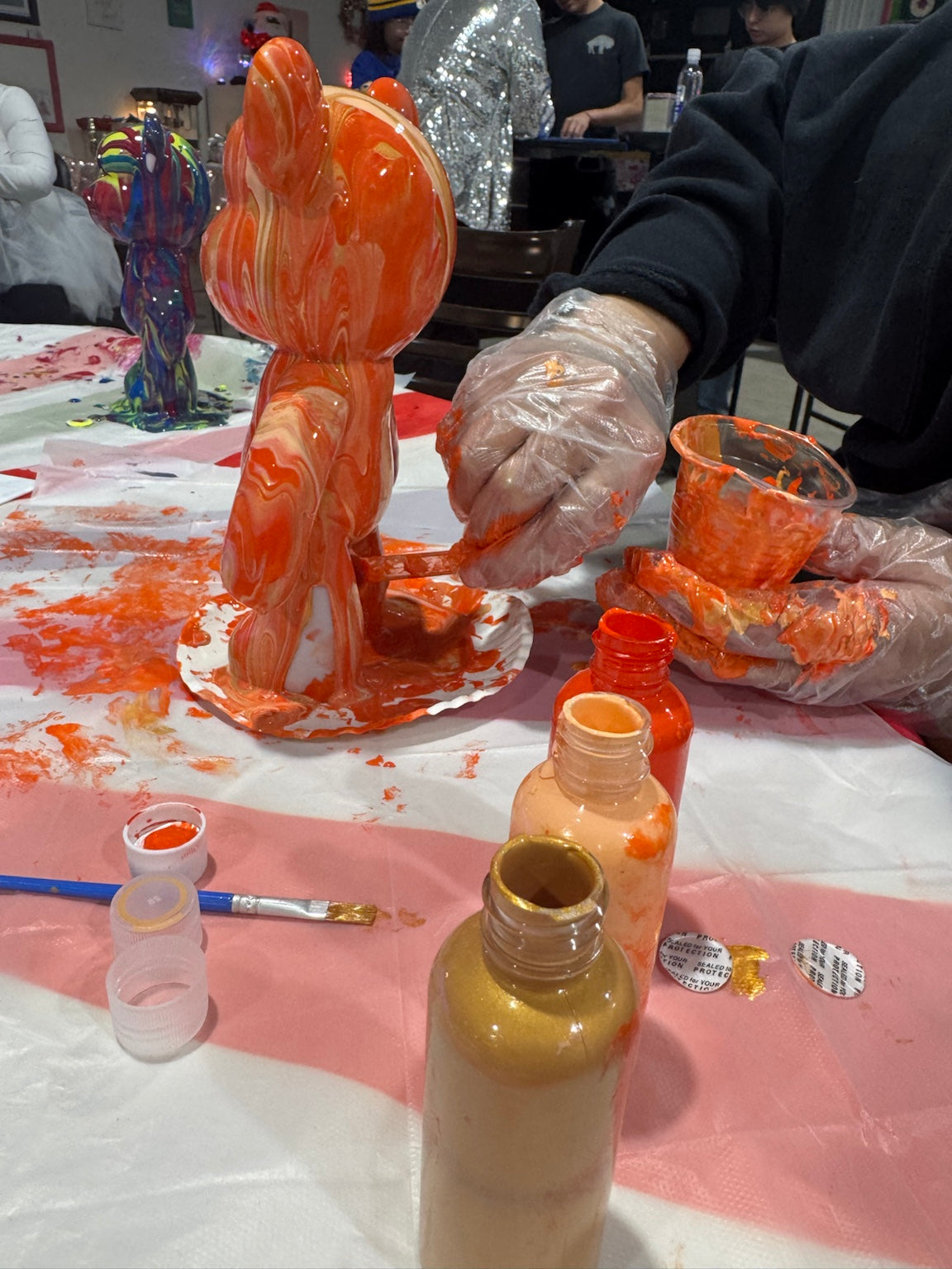Guest painting an orange Drip Bear during a Boom Bear mobile creative party