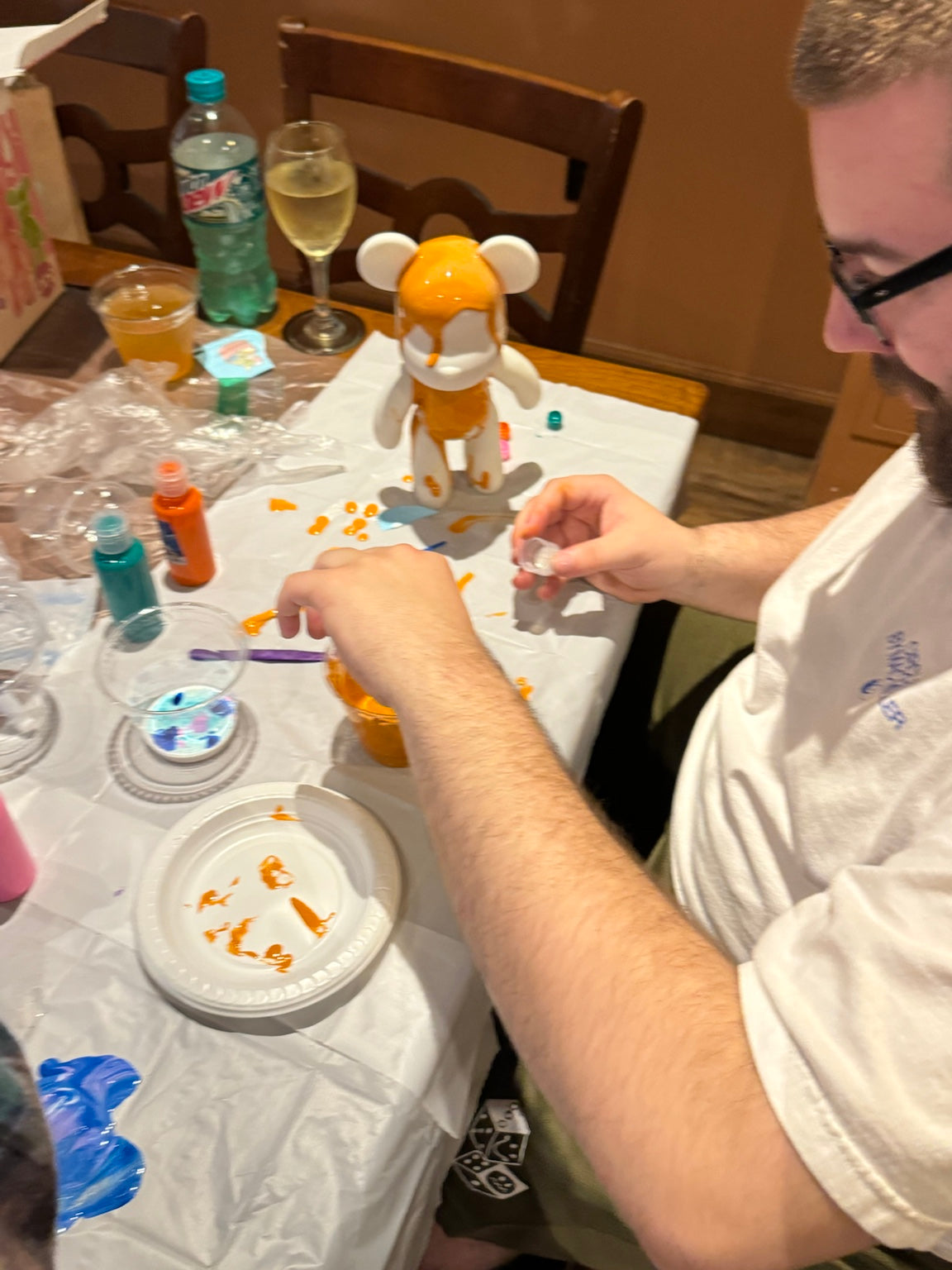 Guest adding paint details to an orange Drip Bear during a Boom Bear creative workshop