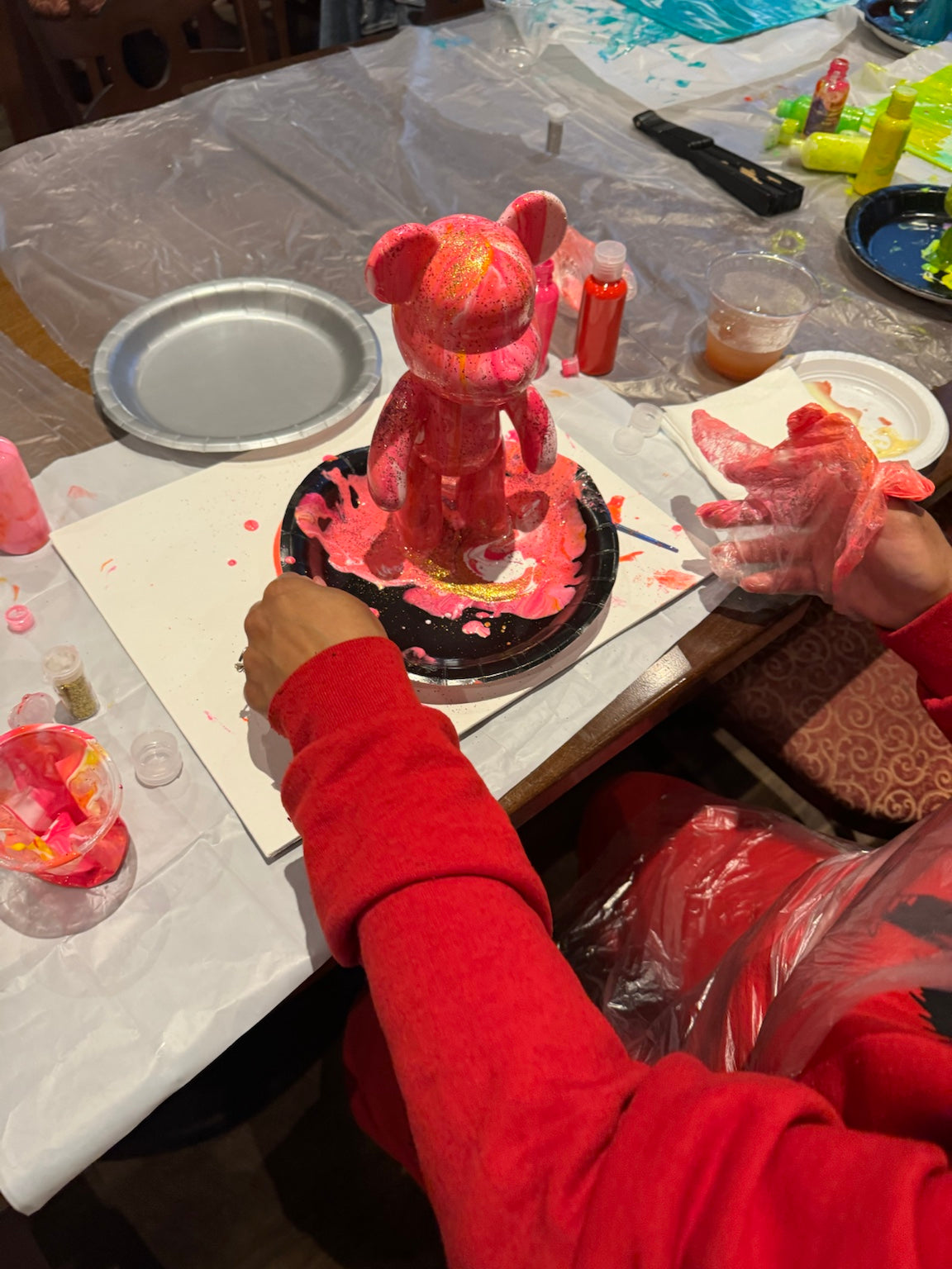 Guest customizing a red Drip Bear during a Boom Bear paint party by Spill Your Creativity