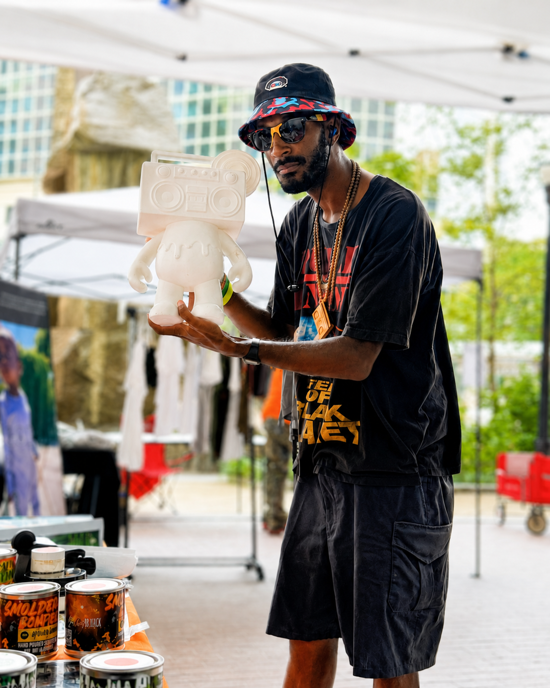Customer holding a white Boom Bear figure under a vendor tent at a community market