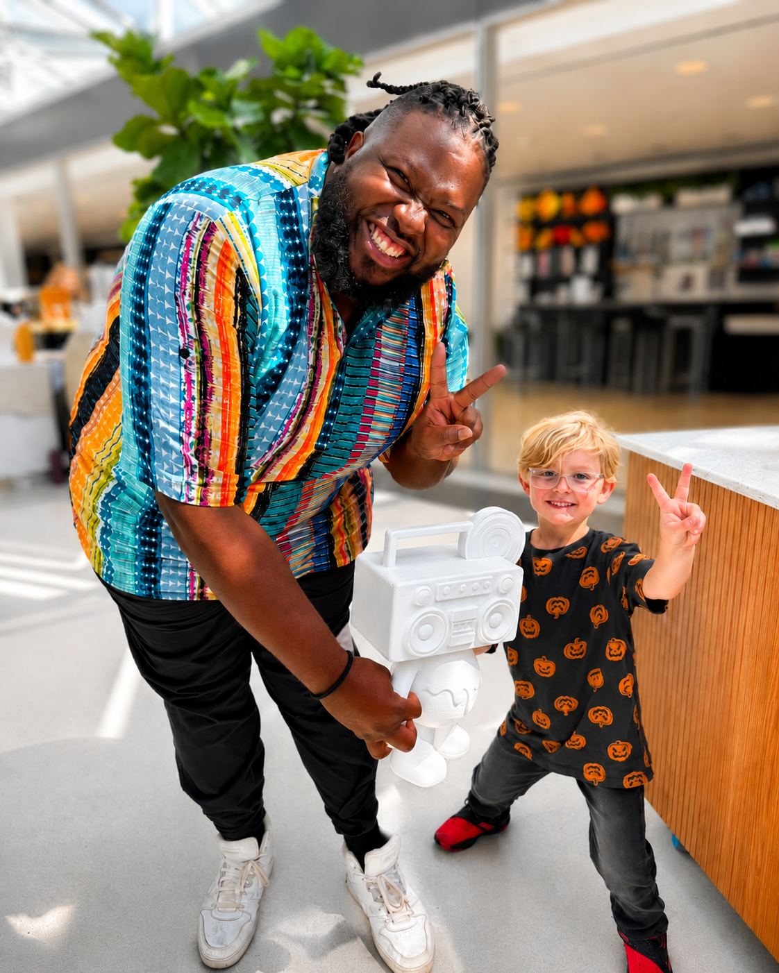 Sterling posing with a child and a large white Boom Bear figure at an indoor event