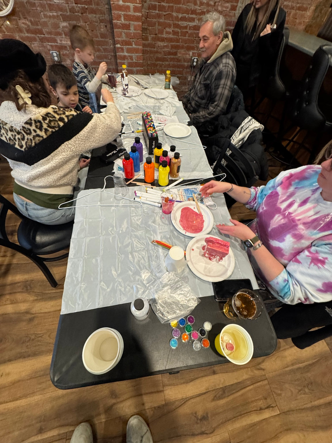 Guests gathered around a table creating colorful Drip Bears during a Boom Bear mobile paint party