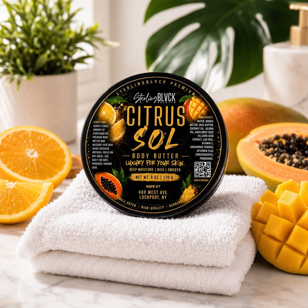 SterlingBLVCK Premium Citrus Sol Body Butter in a bright spa setting with white towels, orange, mango, and papaya.